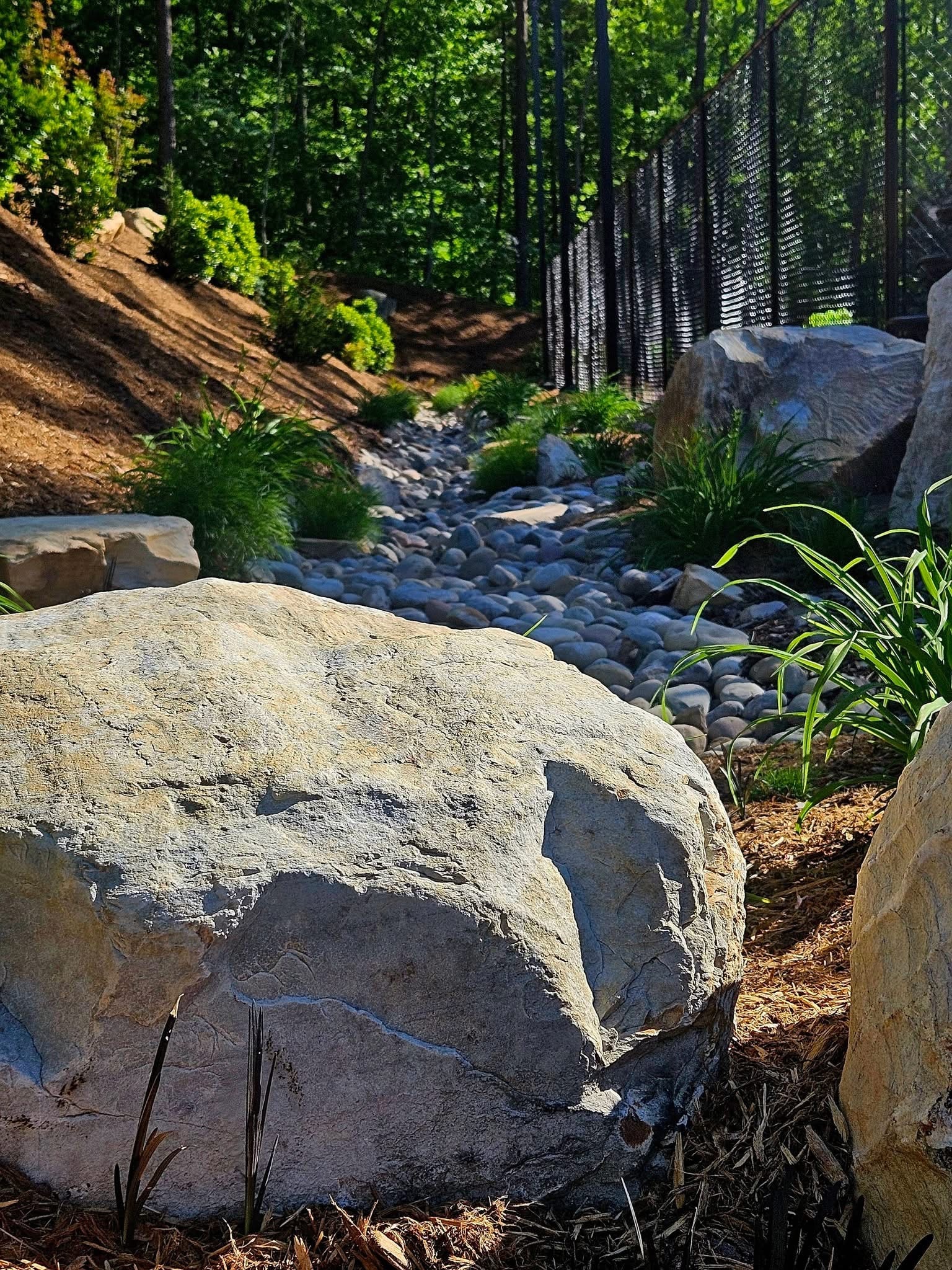 A freshly landscaped garden bed with shrubs and a stone walkway beside a home