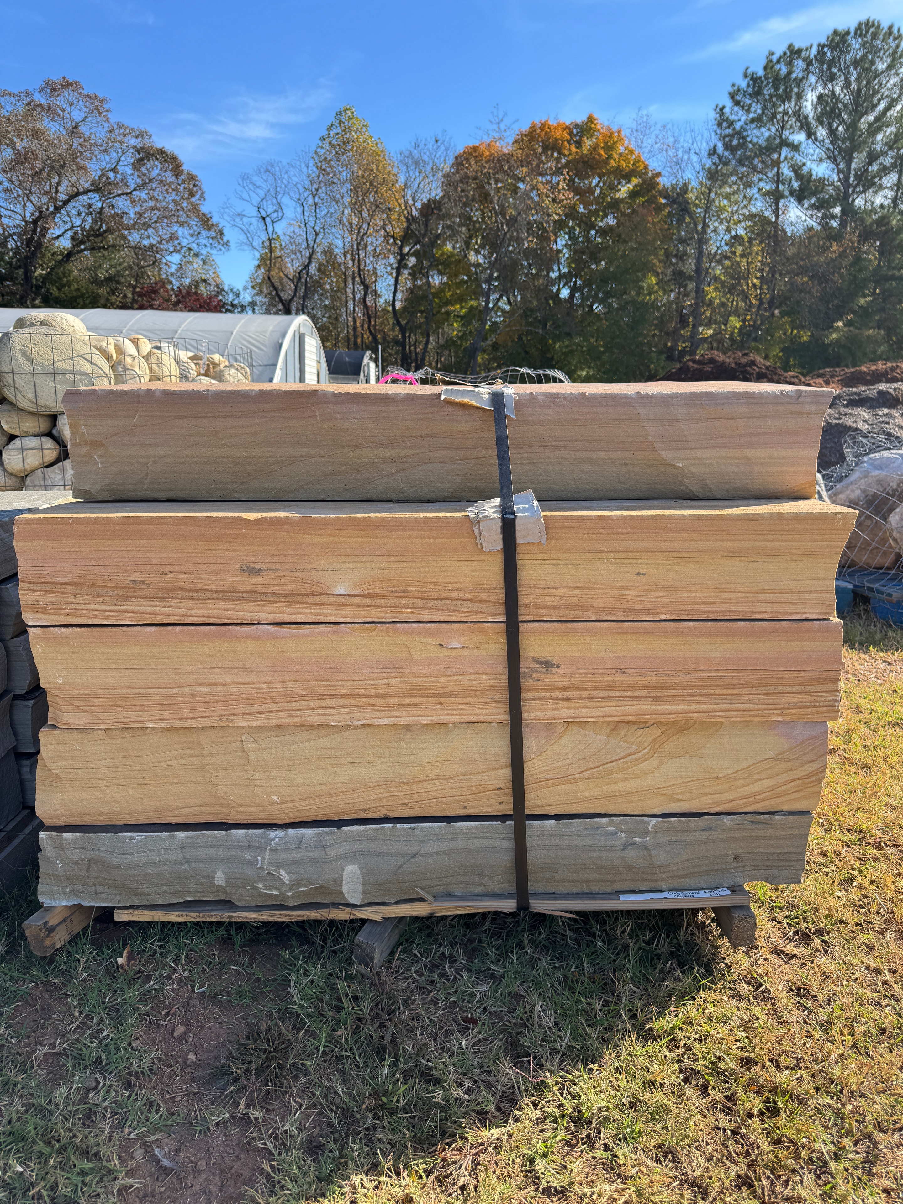 Pallet of Crab Orchard sandstone steppers in warm gold and rust tones strapped on grass