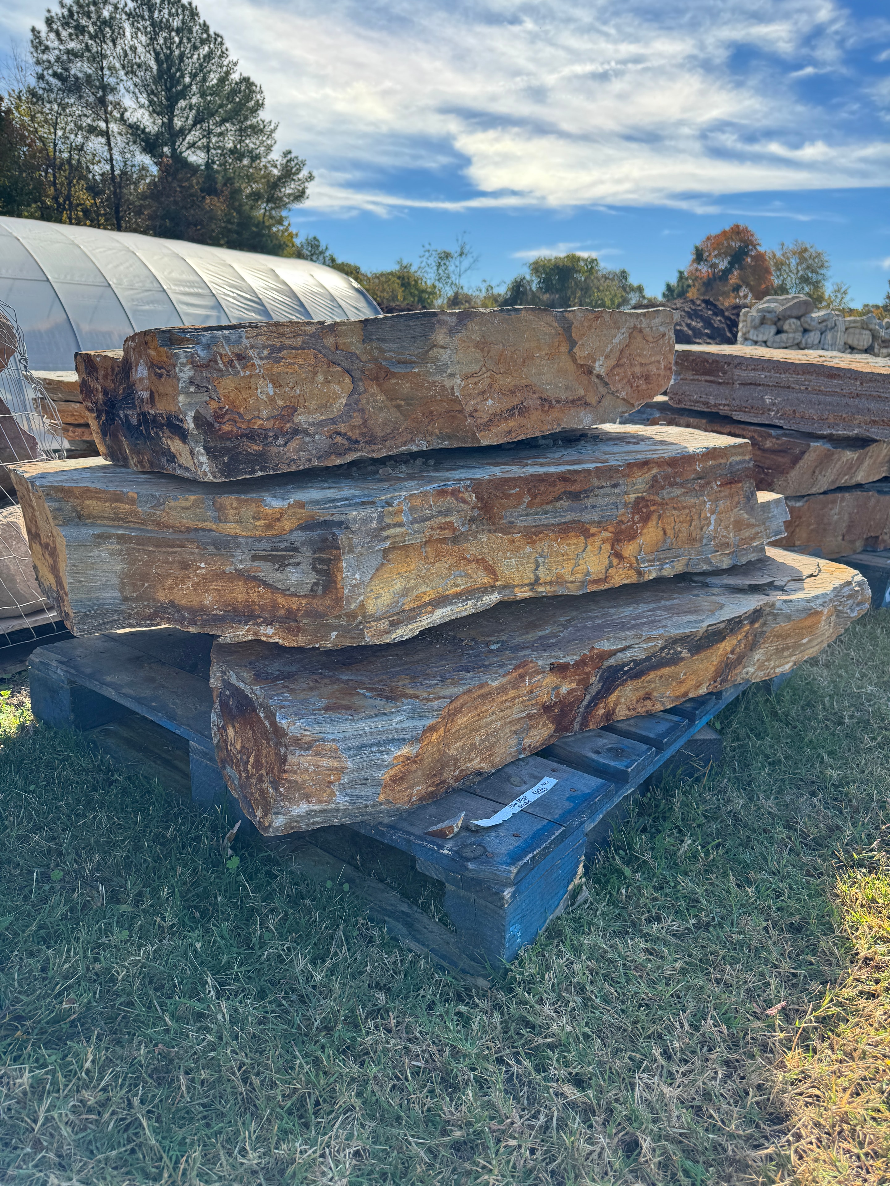 Large Mountain Mist stone slabs with orange and gray banding stacked on a pallet