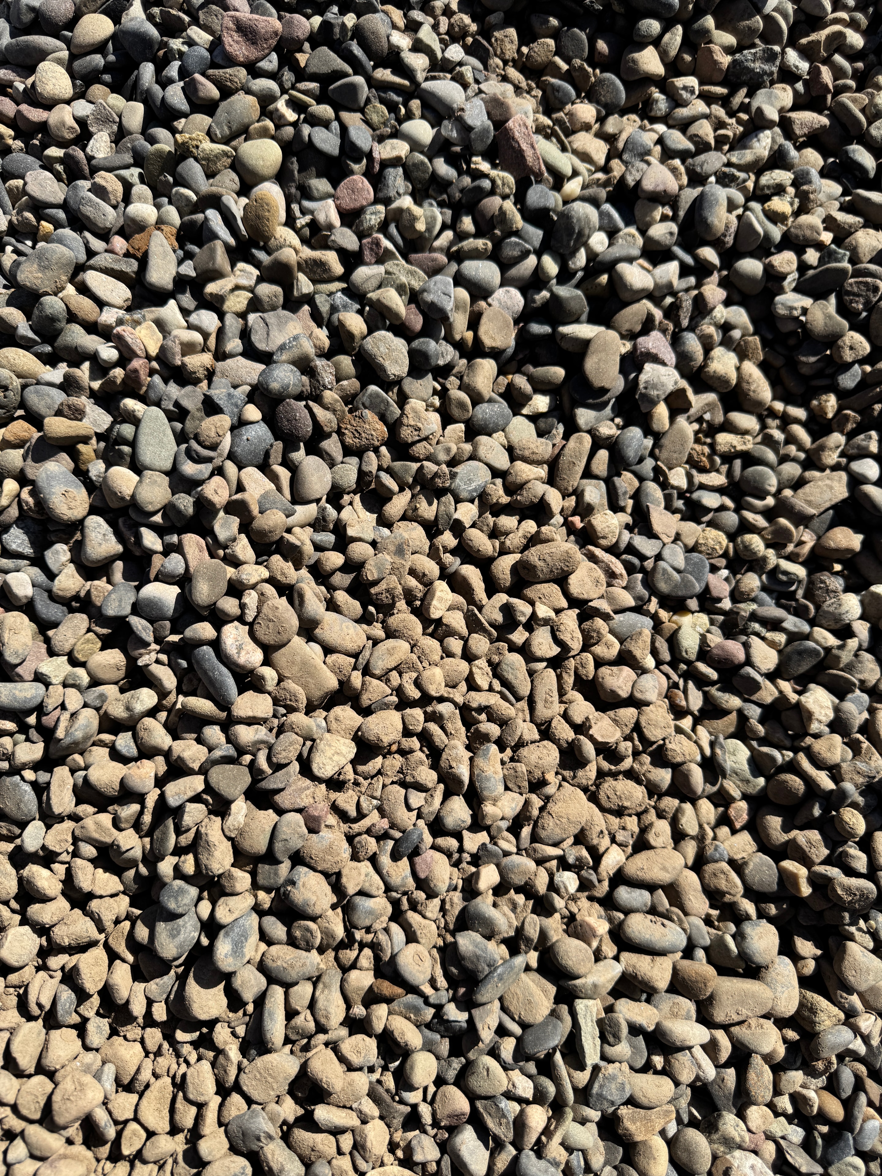 Close-up pile of smooth Pennsylvania pea gravel in tan and gray tones