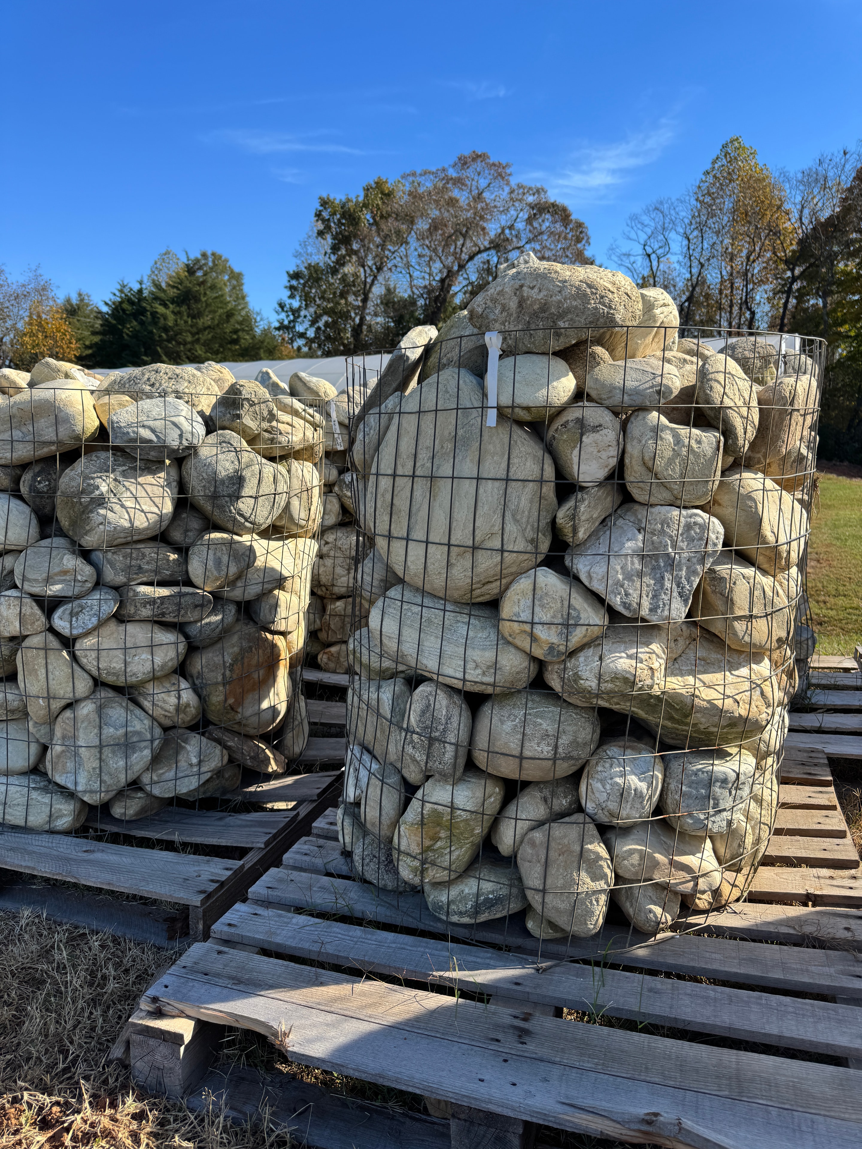 Wire baskets of large smooth river rocks stacked on wooden pallets